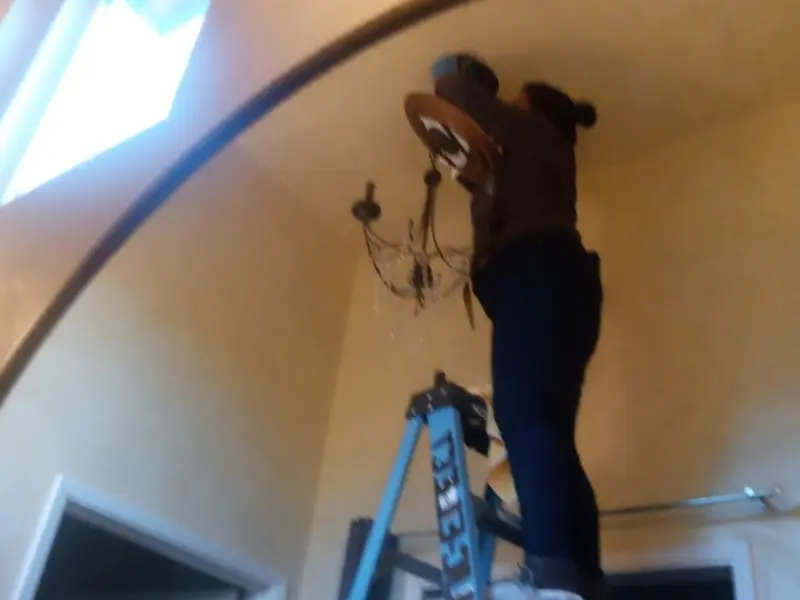 Electrician installing a chandelier in a Oakdale residence